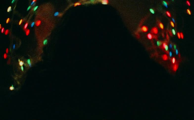 Woman with a happy expression lies in a room with colorful lights