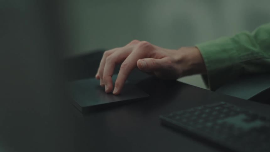 Man sitting at a table with a keyboard and his hand moving on a touch pad
