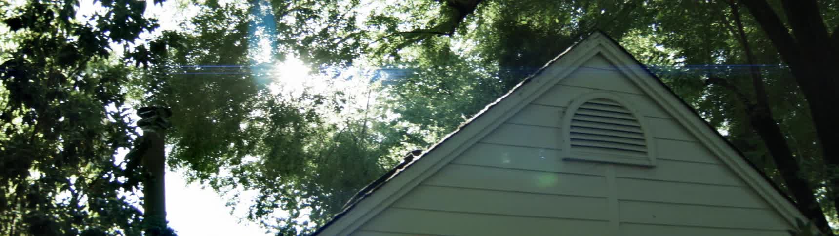 The sun is shining behind the tree of this home