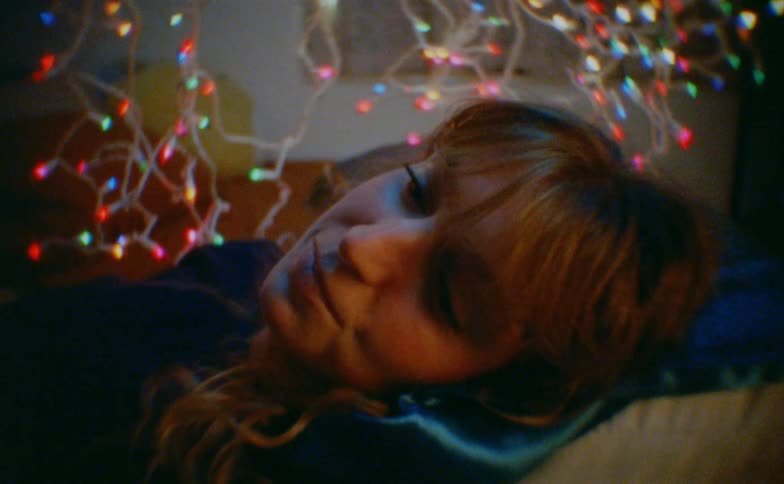 Close up portrait of a happy young woman lying down in a room decorated with colorful lights at night