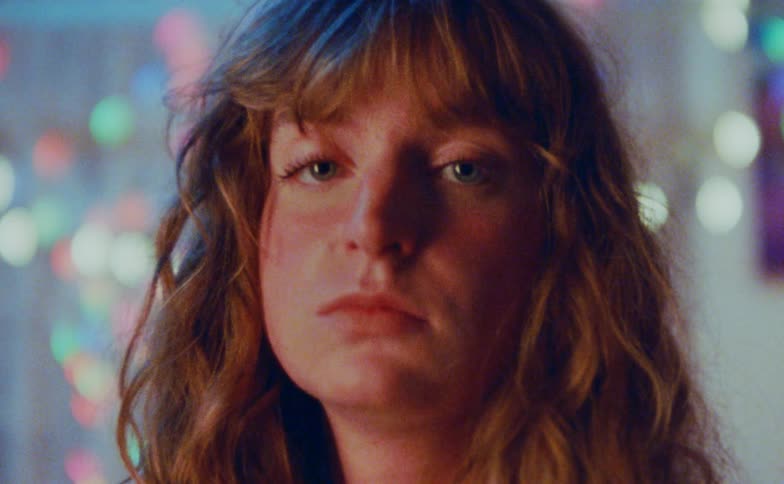 Woman face in closeup with soft lighting and defocused colorful lights in the background