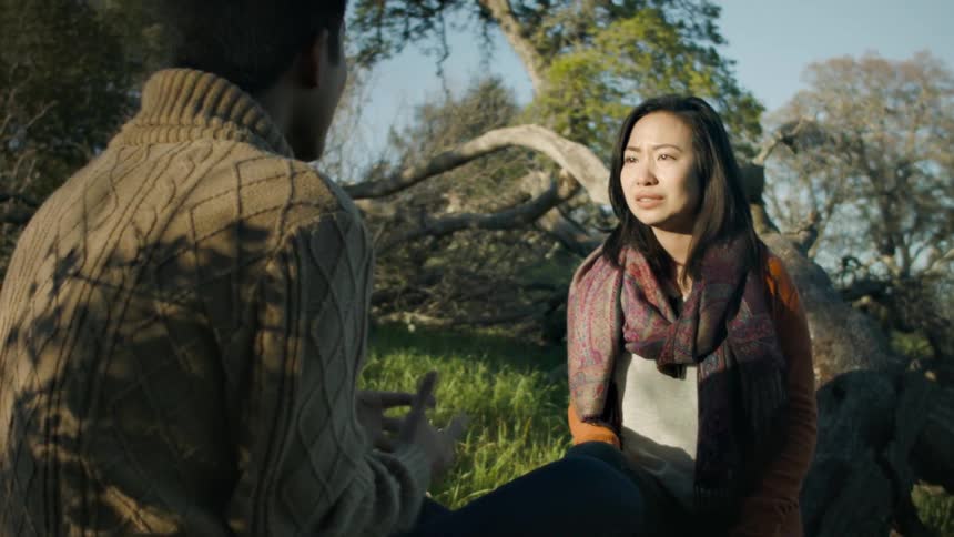 A woman cries while speaking with a man outdoors