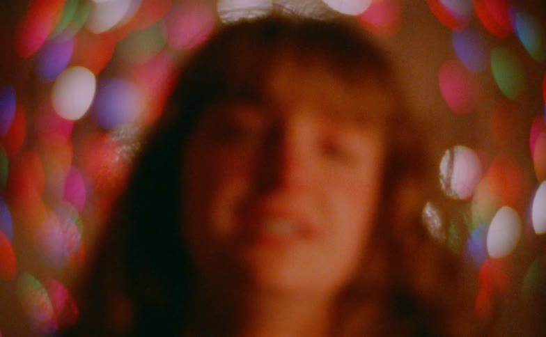 Close up blurry portrait of a sad young woman in front of decorative lights at night