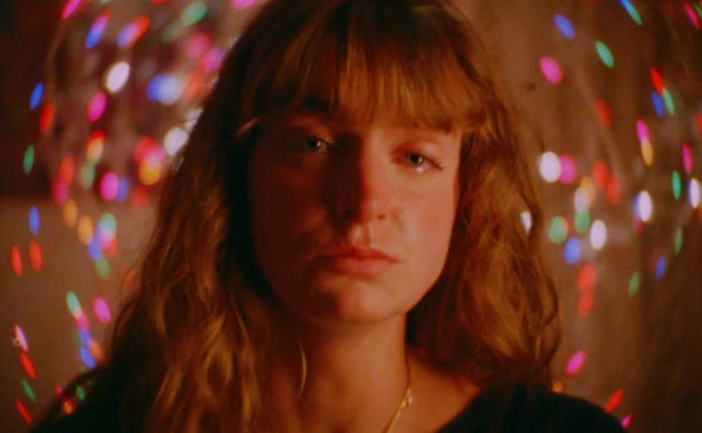 Woman in a room with colored lights and a sad expression