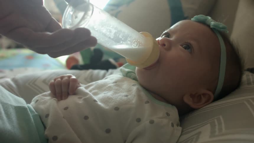 An baby drinks from a bottle
