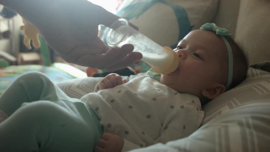 Person feeding a baby a bottle