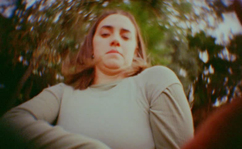 Teenager girl making dance moves around the hands of other dancers with trees on the background outdoors during day time