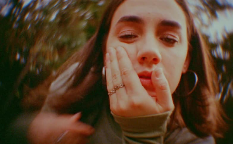 Teenager girl making dance moves with her face and hands with trees on the background outdoors during day time