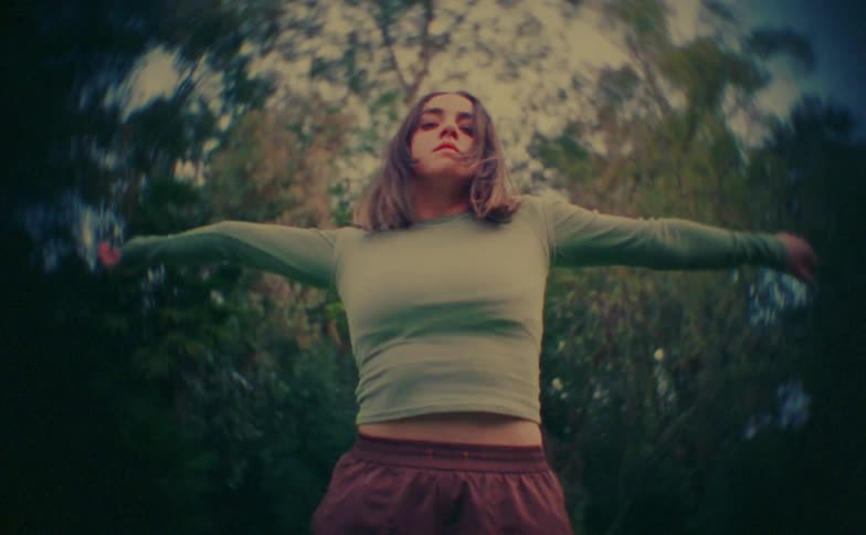 Teenager girl making dance moves in front of trees outdoors during day time