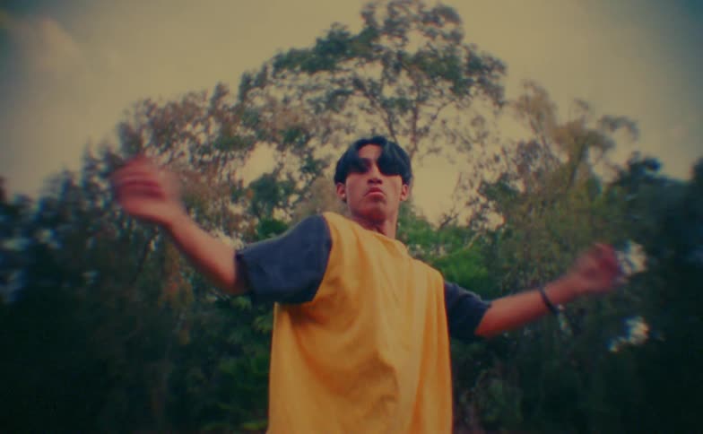 A man dancing outdoors in front of a tree