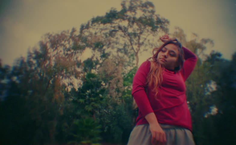 A woman dancingn outdoors in front of a tree