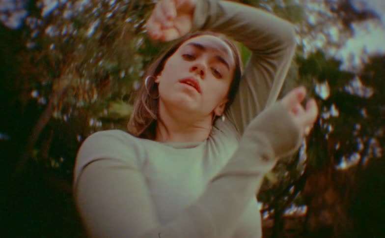 Portrait of a young woman dancing against a backdrop of trees outdoors