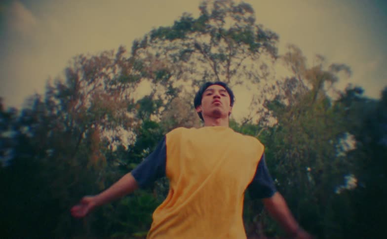 A young man performs energetic dance moves outdoors at midday sunlight highlighting each motion