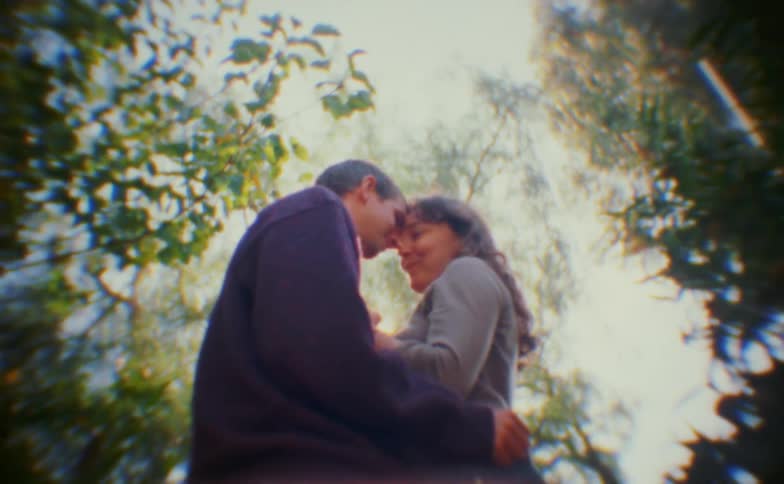 Close up of a young couple holding each other romantically while standing outdoors in a woodland area during daytime