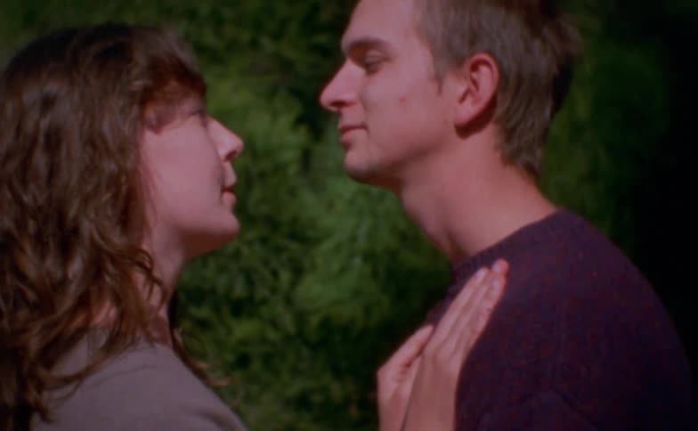 Close up portrait of a young couple conversing romantically while standing together outdoors during daytime