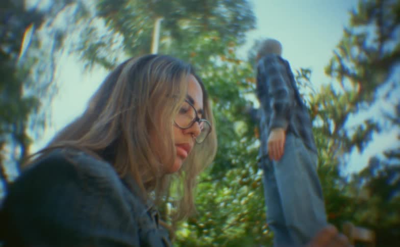Woman is seated and a man beside her is interacting with a tree