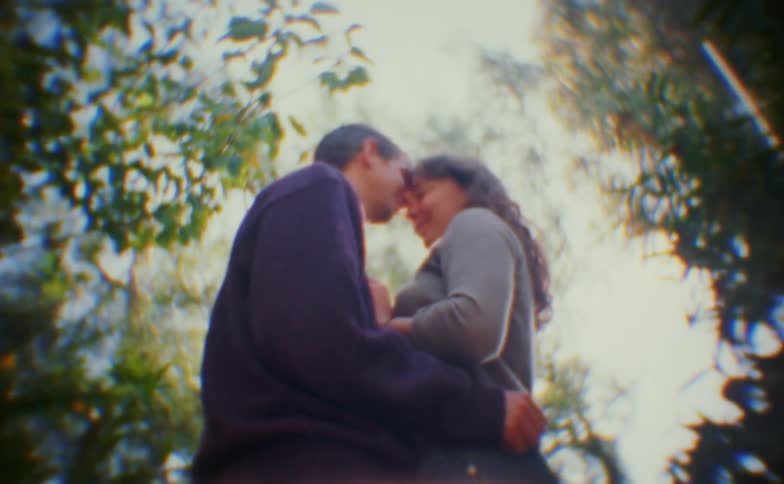 A man and woman kissing in a forest