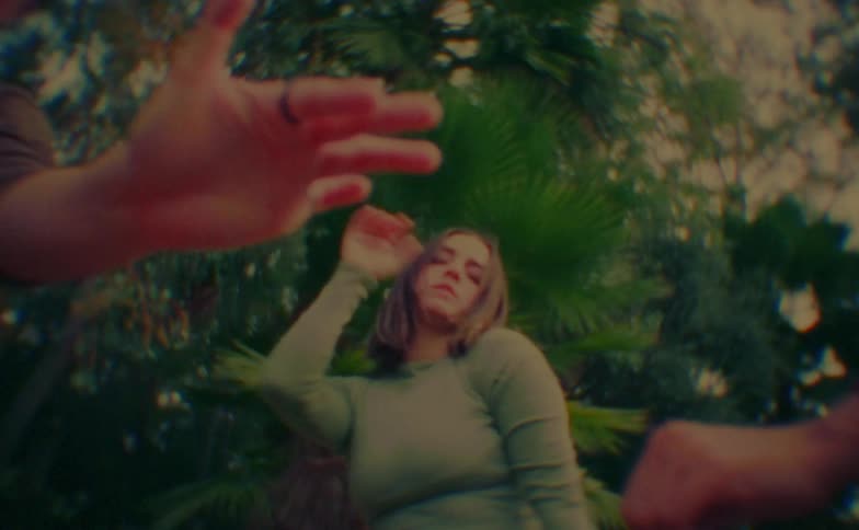 Hands in the foreground and a woman dancing in the background
