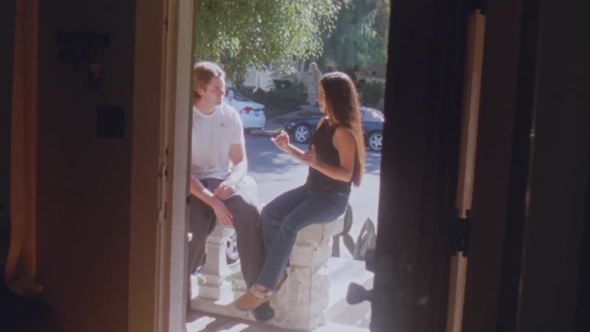A cheerful couple enjoying a lively conversation while sitting in a sun drenched doorway