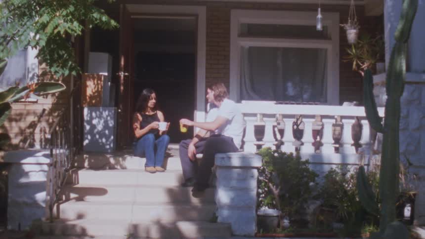 Couple enjoys coffee and conversation together on a sunlit suburban porch