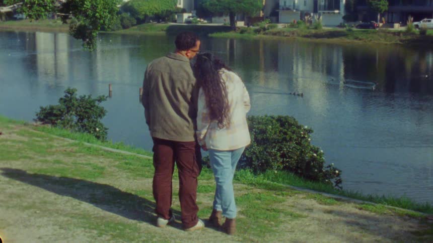 A man and woman holding hands near a lake