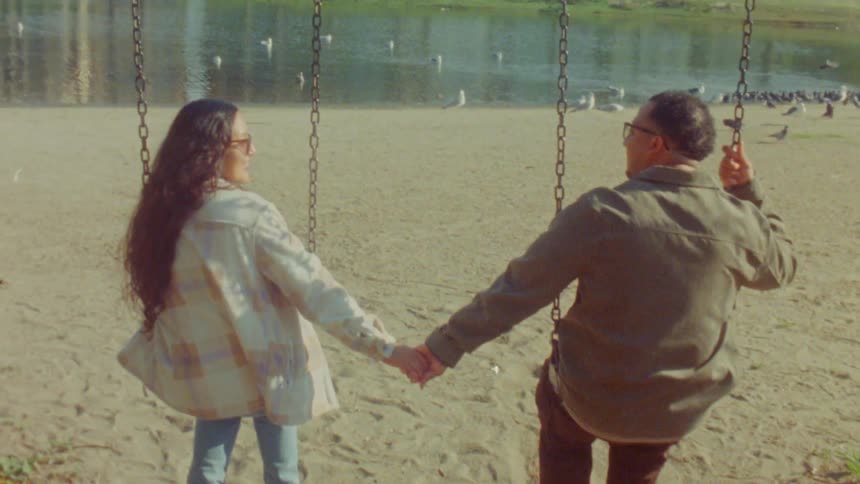 A man and woman holding hands near a lake