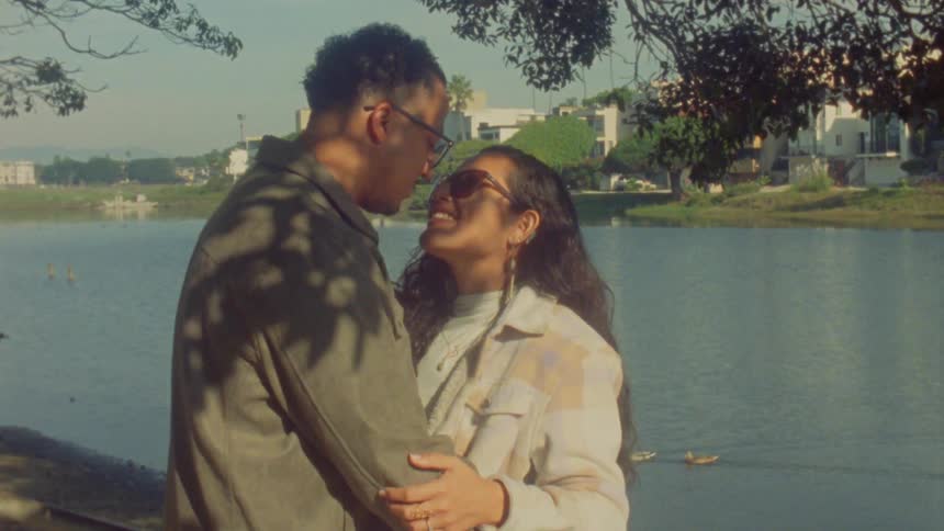 Couple embraces by an urban lake under natural daylight