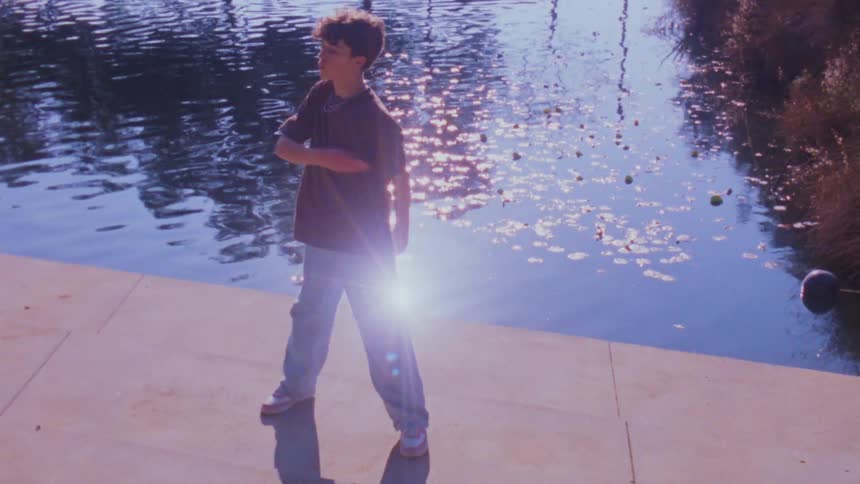 The boy is dancing and spinning by the water