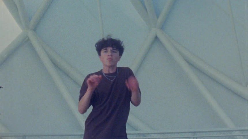 Person performs dance movements in front of a geometric architectural structure indoors