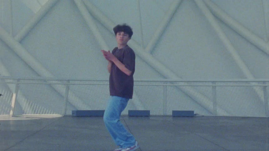 Person performs a jump during dance movements in front of a geometric architectural structure indoors
