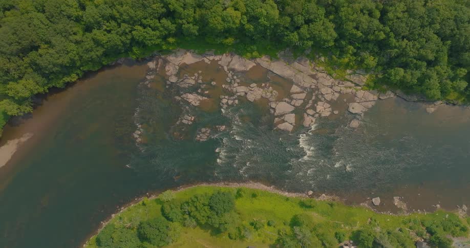 Aerial of a flowing river surrounded by green vegetation during daytime
