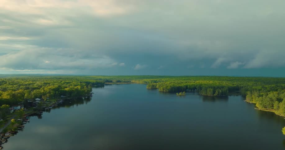 House on the coast of a forested lake under a cloudy sky