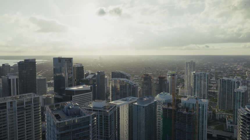 Tall buildings with varied styles and cranes in the background under partly cloudy sky