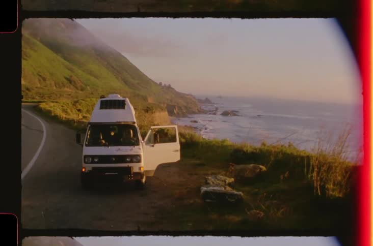 An open camper van parked on a road outdoors by the sea coast during daytime