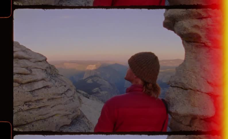 Person looks at a canyon landscape between rock formations under natural light