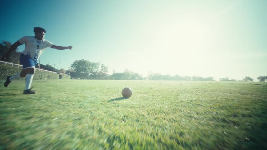 Man runs across the field and kicks a soccer ball