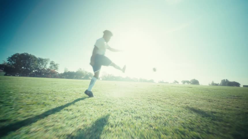Player kicking a soccer ball on a grass field