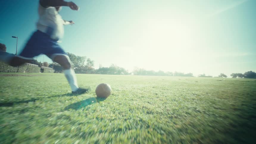 Person kicking a soccer ball on a grass field
