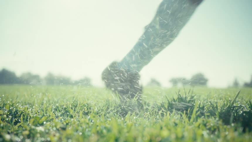 Young man steps up to a soccer ball on the grass and kicks it