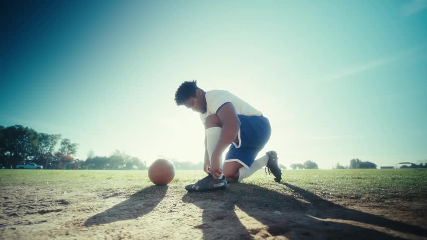 Player on a soccer field tying his shoelaces