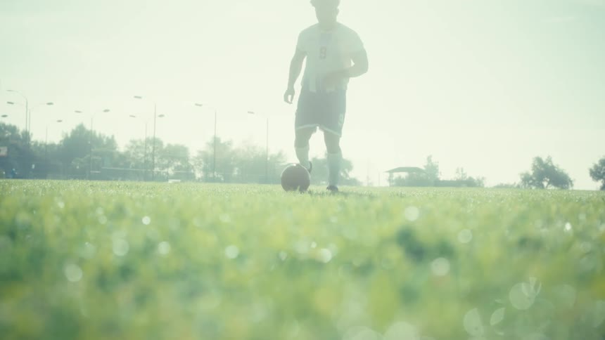 Person running on a grass field with a soccer ball