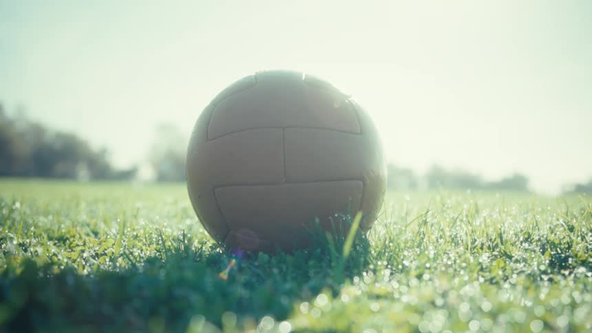 Person positioning a soccer ball on a grass field and then kicking it