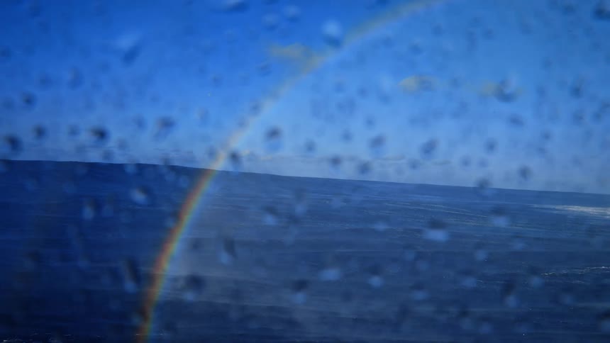 Splashes of water in a blue ocean with a rainbow