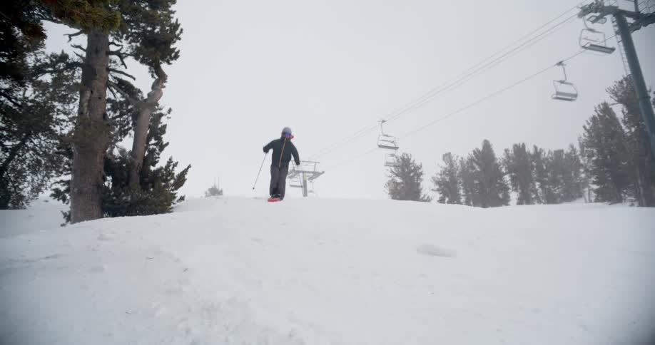 A skier carves downhill on a snowy mountain slope during a winter day