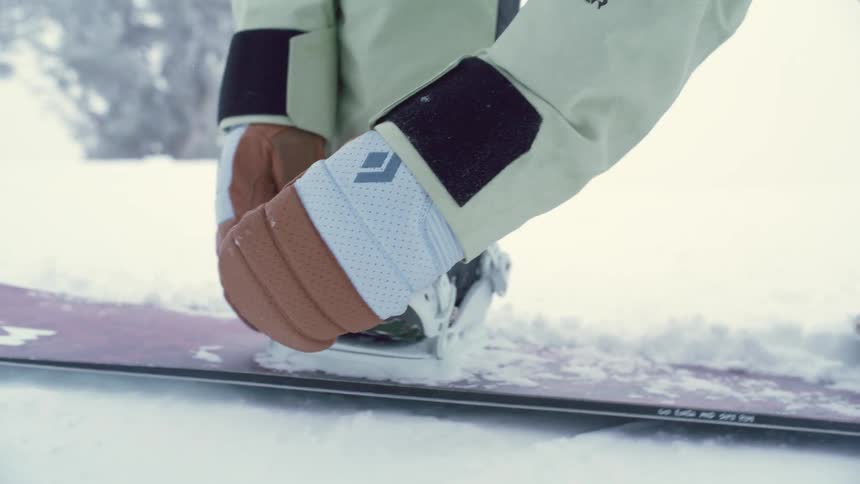Person adjusting their feet on a snowboard in the snow