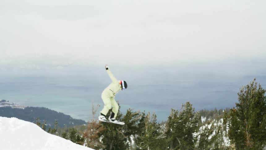 Person performing an aerial snowboarding maneuver in the snowy mountains
