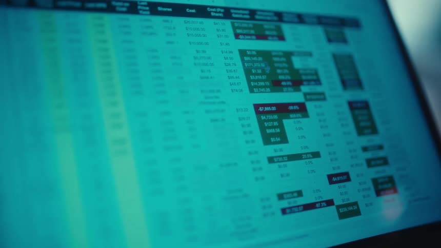A financial spreadsheet with figures for gains and losses is displayed on a computer screen