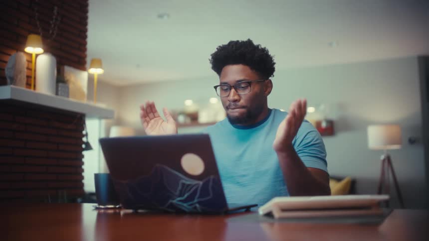 Man is sitting at a table drinking coffee and opening his laptop