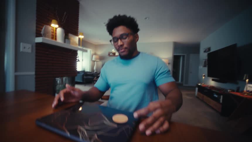 Young man sitting at a table closes the lid of his laptop computer