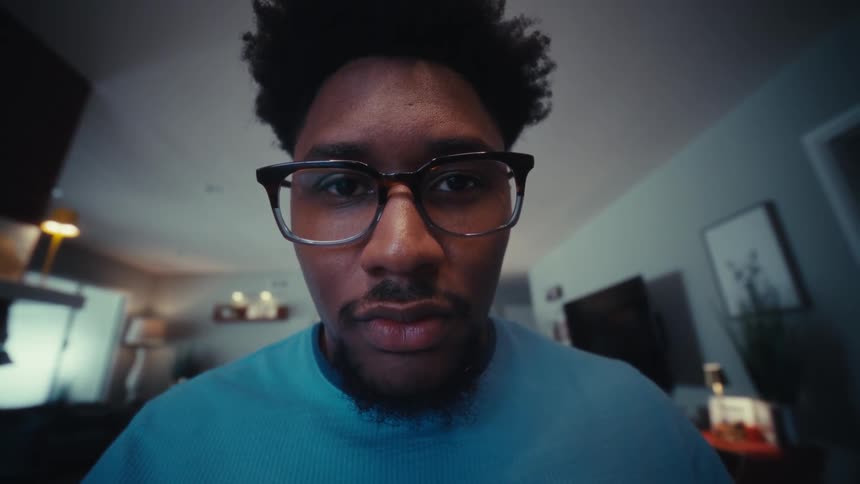 A man types on a keyboard and then looks up his face filling the view as he stares intently forward